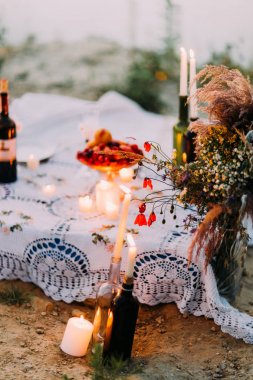 Kır çiçekleri buketi şişelerde parlayan mumları yakın çekim romantik kompozisyon yerleştirilen.