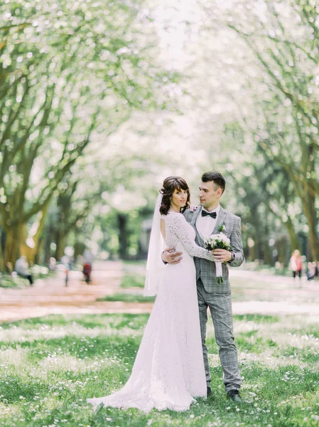 La photo pleine longueur des mariés heureux câlins à l'arrière-plan du parc ensoleillé . — Photo