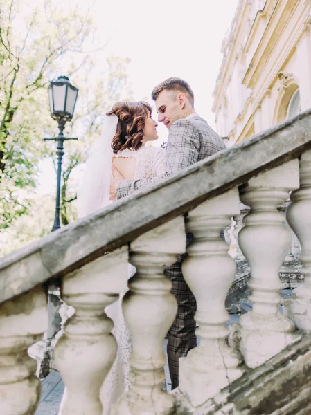 O retrato romântico das costas dos recém-casados abraçados atrás dos velhos barris . — Fotografia de Stock