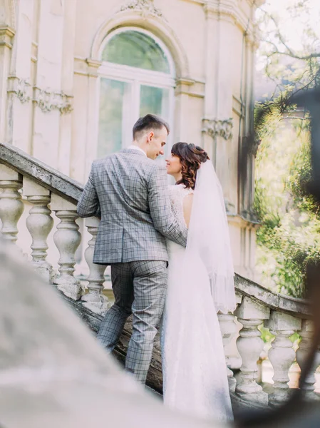 La vue arrière du marié serrant la mariée dans les escaliers de la vieille maison . — Photo