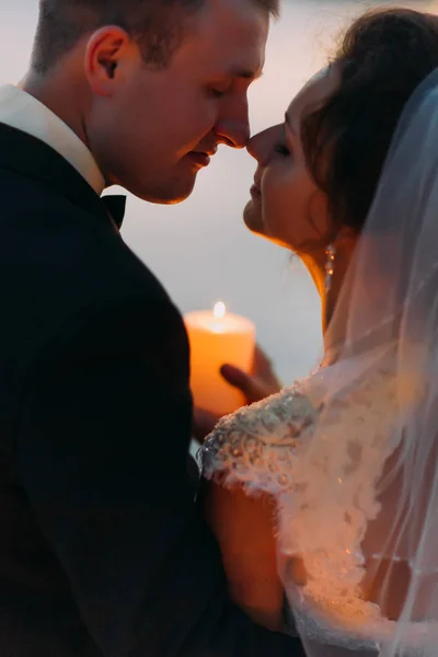 De close-up gevoelig portret van de jonggehuwde paar neus aanraken terwijl de shing kaars. — Stockfoto