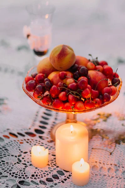 闪亮的蜡烛附近樱桃、 桃子在盘子上的特写视图. — 图库照片