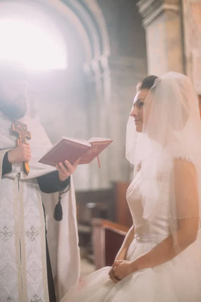 Вертикальні фото нареченої і священик читання Біблії в церкві. — стокове фото