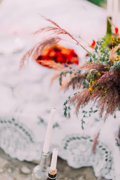 La vista de cerca de las velas en botellas colocadas cerca del ramo de flores silvestres . — Foto de Stock