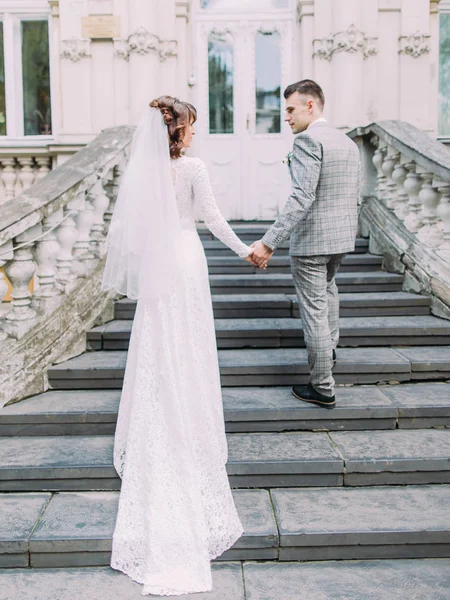 La mariée tient la main du marié et le suit dans les escaliers. . — Photo