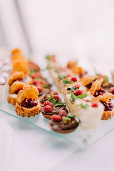 Una gran selección de diferentes postres de boda decorados con frutas y chocolate . —  Fotos de Stock