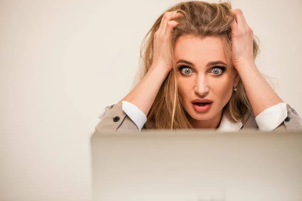 Linda mulher de negócios sentada na frente de seu laptop com a mão no cabelo. Mulher com grandes olhos surpresos . — Fotografia de Stock