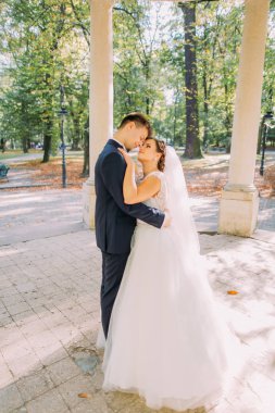 Eski oyuk sarılma newlyweds romantik bakış güneşli parkta yer.