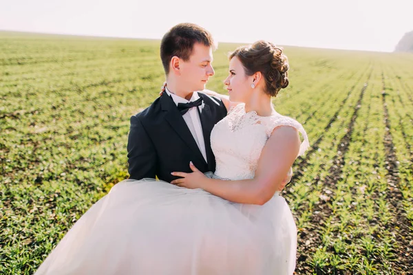 Vista de cerca del novio que lleva a la novia en el campo verde . — Foto de Stock