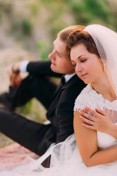 Das Nahaufnahme-Porträt der Frischvermählten, die Rücken an Rücken sitzen. — Stockfoto