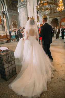 Uzun gelinlik gelin ve damadın Kilisesi töreni sırasında arkadan görünüm.