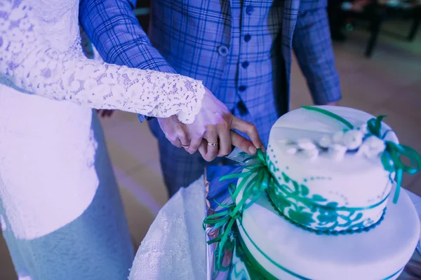 Detailní pohled řezání první kousek svatebního dortu novomanželé rukou. — Stock fotografie