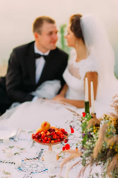 Die Nahaufnahme der Picknick-Komposition vor dem verschwommenen Hintergrund des fröhlichen Brautpaares. — Stockfoto