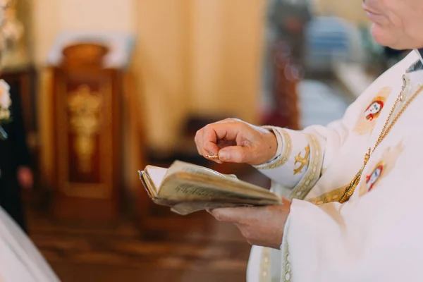 Den horisontale synsvinkelen til presten som holder gifteringen over boken i kirken . – stockfoto