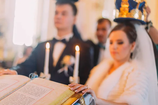 A vista de perto da parte do livro colocada no fundo borrado dos recém-casados com coroas douradas . — Fotografia de Stock