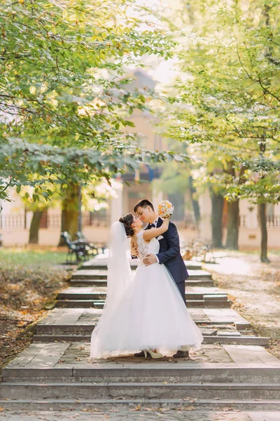 Lyckligt nygifta kramas i parken under soliga dagen. Fullängds Visa. — Stockfoto