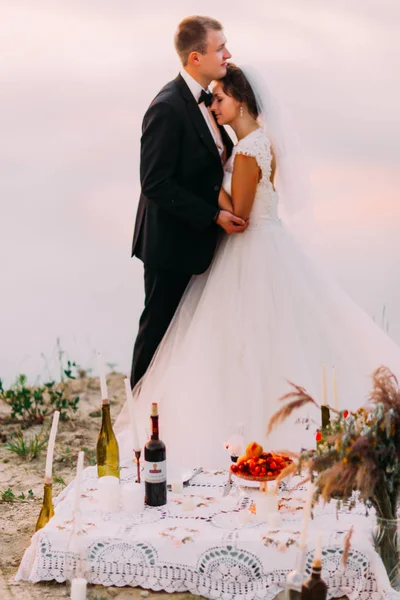 De romantische picknick instellen op de onscherpe achtergrond van de knuffelen pasgetrouwden. — Stockfoto