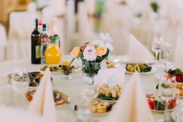 Букет желтых и розовых цветов в вазе, поставленной на стол в окружении блюд — стоковое фото