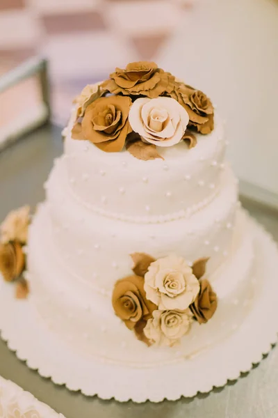 Die Nahaufnahme der weißen Hochzeitstorte, die mit Schokorosen dekoriert ist. — Stockfoto
