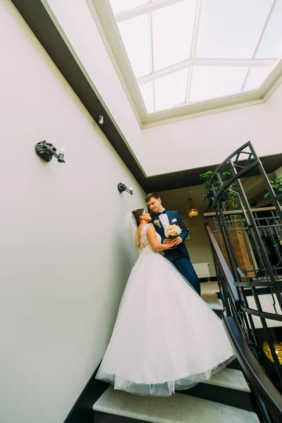 A vista vertical dos recém-casados felizes em pé nas escadas . — Fotografia de Stock