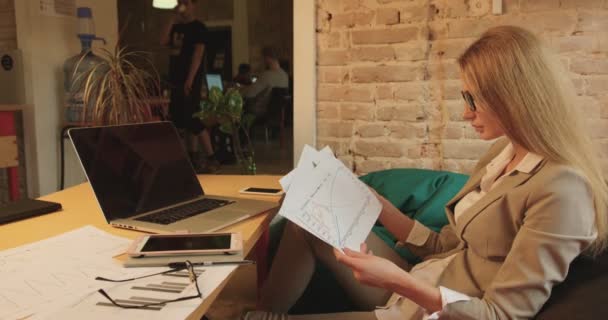 La vue de côté de la femme d'affaires travaillant avec les graphiques tout en étant assis dans le café . — Video