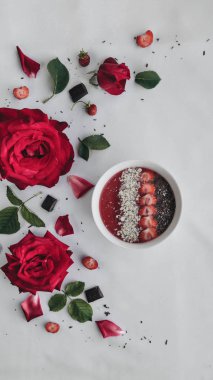 Çikolata ve çilek kırmızı gül ve yaprakları dolu masada lezzetli çay görünümünü süslenmiş.