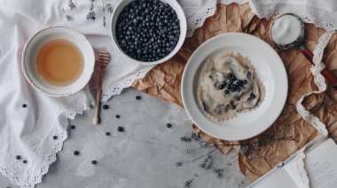 Çay fincan rustik bileşimi görünümünü, yaban mersini ve kahvaltı yemek dolu plaka.