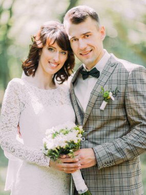 Gülümseyen yeni evliler düğün buket parkta tutuyorsun.