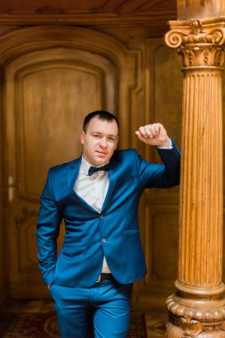 Eski sütun üzerinde eğilerek damat tam uzunlukta portresi.