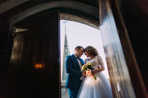 Felizes recém-casados na varanda da antiga catedral gótica. Vista da porta — Fotografia de Stock