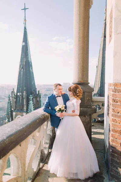 Happy bride and groom posing on the balcony of old gothic cathedral — Stock Photo, Image