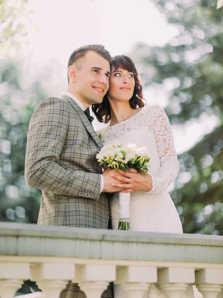 Les jeunes mariés tiennent le bouquet de mariage et profitent du temps dans le parc du printemps . — Photo