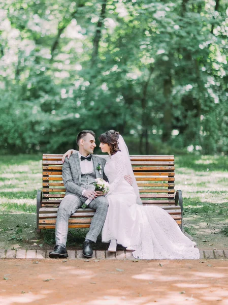 A szemkontaktus a newlywed pár ül a padon a parkban. — Stock Fotó