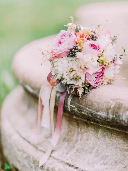 Крупним планом весільний букет з різнокольорових півоній, що лежать на фонтані . — стокове фото