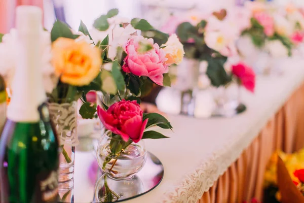 Schöne Mini-Vasen mit bunten Rosen auf dem Hochzeitstisch. — Stockfoto