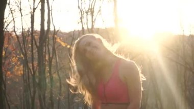 Mutlu güzel kadın atlama ve baş günbatımı sırasında sonbahar parkta sallayarak..