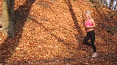 Sonbahar park boyunca koşu ince sportwoman yan tam uzunlukta görünüm.