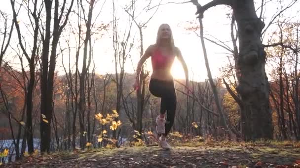 Die ganzheitliche Ansicht der Sportlerin, die im Herbstpark springt. — Stockvideo