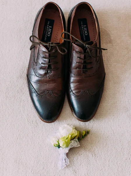 A visão para cima da composição consistiu nos sapatos de casamento homem e boutonniere de rosas brancas . — Fotografia de Stock