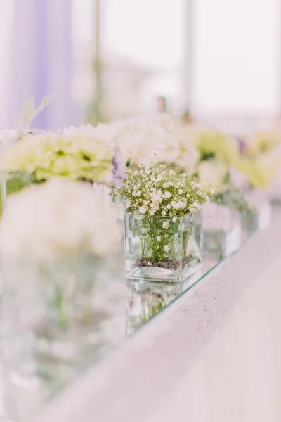 El hermoso jarrón rectángulo con pequeñas flores blancas en . — Foto de Stock