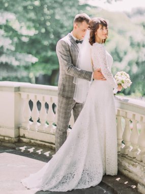 Balkonda arkadan sarılma gelin damat tam uzunlukta görünüşü.