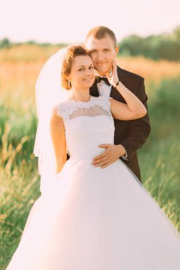 Gülümseyen damat geri neşeli gelin alanında sarılıyor.