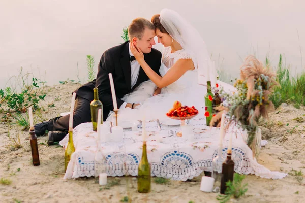 Os recém-casados estão sentados perto do piquenique de casamento na praia . — Fotografia de Stock