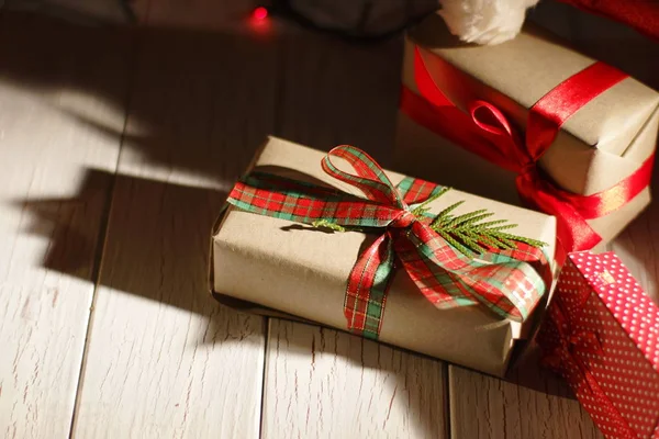 Close-up view of the lovely Christmas gifts wrapped in colourful pape and red ribbons. The gift is decorated with a leave of the Christmas tree.