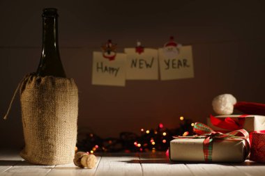 Arka plan bulanık parlayan çelenk ve ipe asılı mutlu yeni yıl işareti, antient şişe şarap Noel yakınındaki sunar.