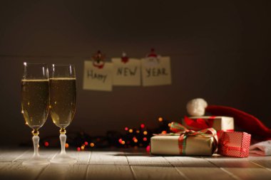 Yeni yıl iki bardak şampanya Noel hediyeleri, parlayan çelenk ve yeni yıl işaretleri arka plan bulanık, romantik bileşimi.
