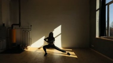 Genç çekici kadının yan yapması yakın çekim yatay görünüm karanlık stüdyoda lunges.