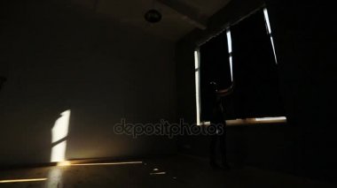 Atletik kadın pencereye gidiyor, siyah perdeleri çekerek ve bacaklar kaldırma. Stüdyo konumu.