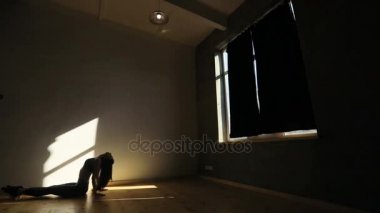 Sportwoman katta oturan, Karanlık odanın penceresi geliyor, siyah perdeleri çekerek ve ısınma.