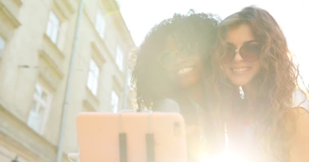 İki sevimli gülümseyen kız selfie yaparken hava öpücük gönderme yakın çekim portre. Onlardan biri Afro-Amerikan. — Stok video